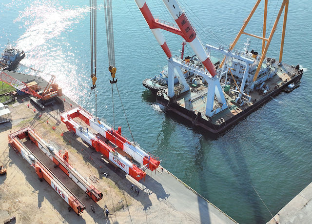 海上クレーンで海岸クレーンのブームの更新作業をしている様子